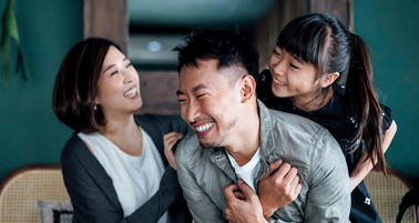 Playful young Asian family having fun playing at home while mother and daughter tickling father in bed. Family life with love and happiness
